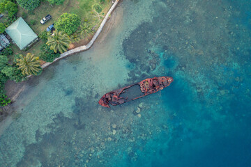 Abandoned broken sunken old ship that ran aground. Drone view. Tropical coast of Sanma, Vanuatu.