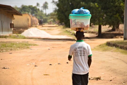 Chico africano cargando comida en la cabeza en Sierra Leona