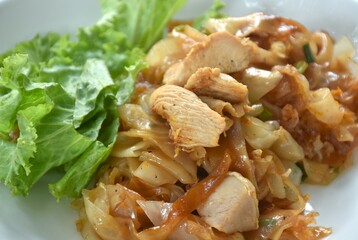 spicy fried large rice noodles with chicken and slice lettuce on plate 