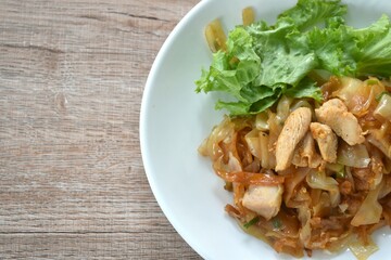 spicy fried large rice noodles with chicken and slice lettuce on plate 