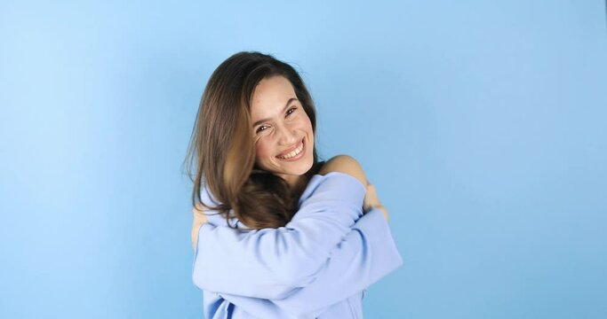 Come into my arms. Adorable happy girl with brown hair in blue top gesturing come here for free hugs and smiling sincerely with welcoming expression isolated on blue background. Come to me, hug self.