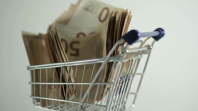 shopping cart with 50 euro note bills on white background 