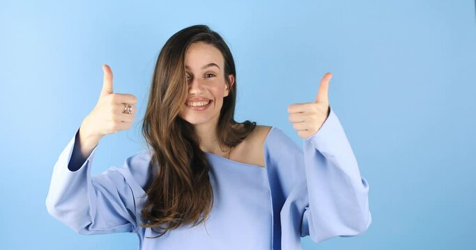 Young woman making good-bad sign isolated on blue background. Girl make choice, or makes a decision thumb up or thumb down, like or dislike, yes or no. Woman change emotions, raised hands.
