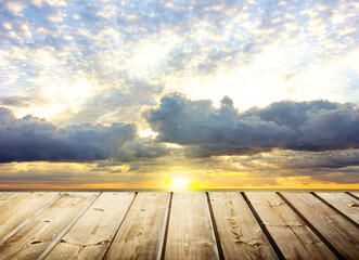 Fototapeta na wymiar Wooden table with gray cloud background with sunset light