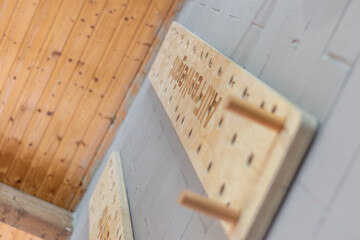 A wooden climbing board or pegboard hung on the wall. Focus selectec