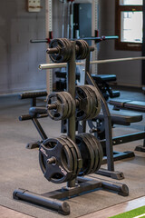 A black weight rack with several sets of barbell discs on it.