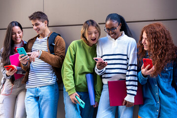 Multiethnic group of students browsing mobile phone apps outdoors.