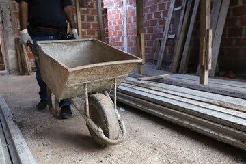 Construction worker. Builder. Bricklayer loading wheelbarrow at construction site. Concept of...