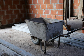 Wheelbarrow at home construction site. Loading tool for bricklayers and builders. Conceptual image...