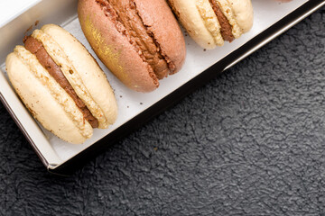 Macaroons in a black cardboard box on a dark background.
