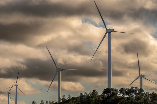 A field of wind turbines stands under a cloudy sky in Tarragona, Catalonia, Spain, marking the region's commitment to green energy