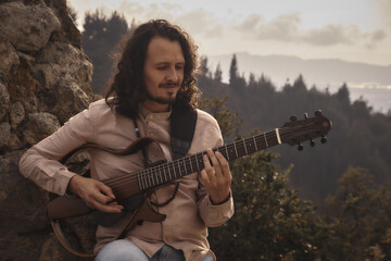 man playing guitar in the mountain