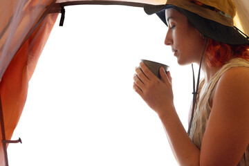 A woman is drinking coffee in a tent. The tent is orange and the woman is wearing a hat