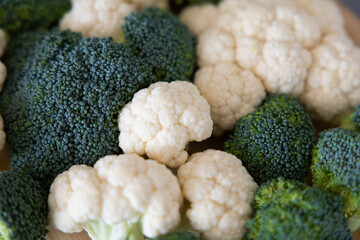 fresh broccoli and cauliflower in a bowl and on the table