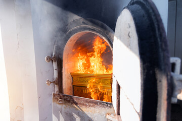 Crematorium door open with flame on coffin from cremate funeral human body cremation ceremony of religion buddhist in temple of Thailand.  - obrazy, fototapety, plakaty