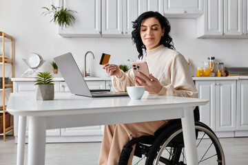 Woman in a wheelchair managing finances and working online using a laptop in her kitchen.