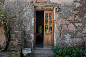 Puerta muy antigua de entrada a una casa, imagen horizontal, muro de piedra, detalles de verde