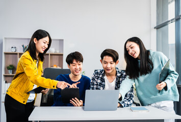 university classroom, diverse group of young students Asian collaborate study together, sharing smiles and insights around desks, exemplifying the joy of learning and friendship in higher education.