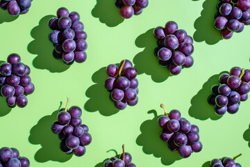 Fresh ripe purple grapes on green surface with shadows, close up shot