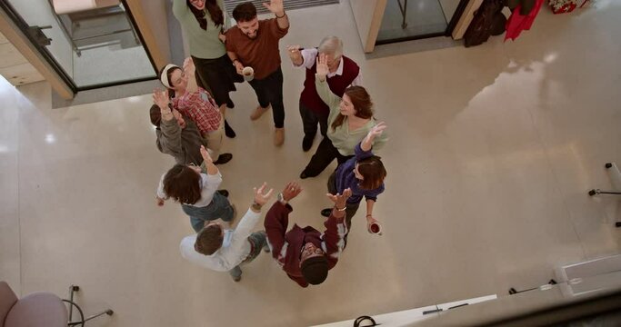 Top view captures a team of multiracial workers coming together, hands joined in unity, demonstrating teamwork and collaboration, showcasing their commitment to working together towards common goals.