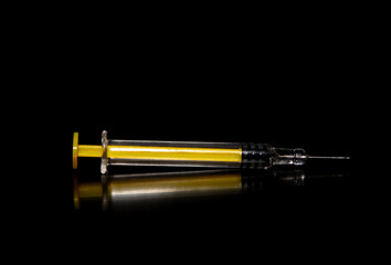 Close-up of a yellow syringe on a black background