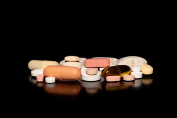 Close-up with a pile of different medicine pills on a black background