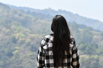 Chica joven Guatemalteca de espaldas admirando el paisaje en las montañas de Guatemala, concepto de paz y relajación.