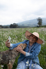Adult woman petting her dog while taking a photo with her mobile phone