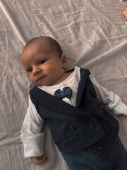 A beautiful baby portrait of a new born boy. The child is dressed smartly, wearing a three piece suit, bow tie and flat cap.