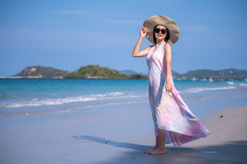 Happy sexy Asian traveller woman wear colorful beach dress and hat show enjoys on tropical beach vacation in summer holidays	