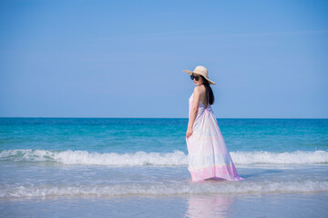 Fototapeta na wymiar Happy sexy Asian traveller woman wear colorful beach dress and hat show enjoys on tropical beach vacation in summer holidays 