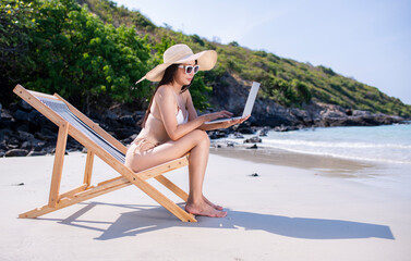 Happy sexy freelance woman wearing bikini sunglasses workout relaxed  with work on laptop computer at beach in summer holidays - 796759693