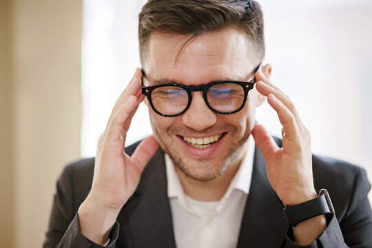 An upbeat executive with glasses exudes joy, showcasing the lighter side of business in a comfortable office setting.