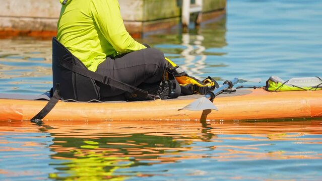 Woman preparing for paddle on board at calm lake water during warm summer. Stand up paddle board with wet suit and life jacket for paddling. Paddle SUP board sport and active recreation.