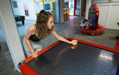 Girl plays air hockey in the entertainment center.