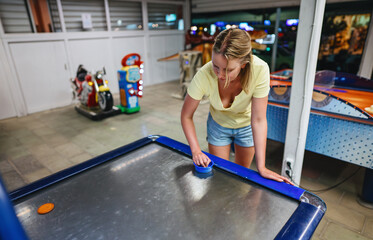 Woman plays air hockey in the entertainment center.