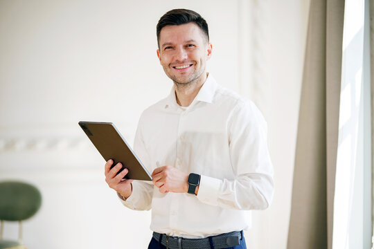 A contented entrepreneur confidently holds a tablet, his smile reflecting the success of his digital endeavors. - Powered by Adobe