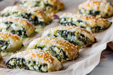 Golden brown spinach and feta pastries topped with sesame seeds.