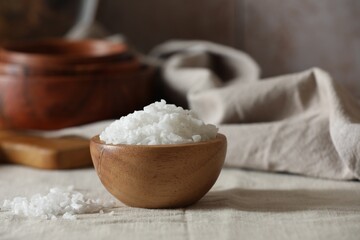 Organic salt in wooden bowl on table, closeup