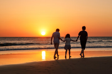 Three kids silhouettes running and jumping on beach at sunset. happy family, two school boys and one little preschool girl. Siblings having fun together. Bonding and family vacation.