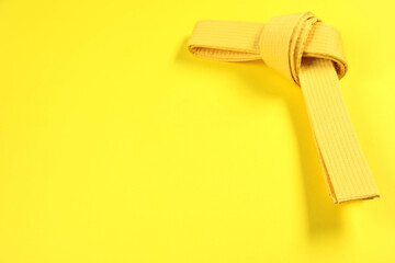 Karate belt on yellow background, space for text