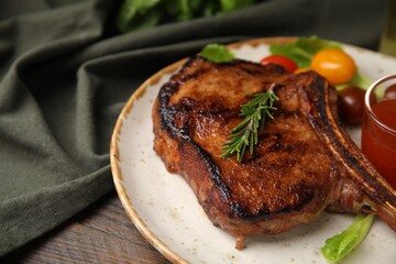 Tasty grilled meat, rosemary and marinade on wooden table, closeup