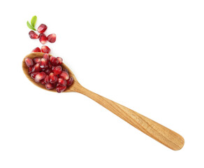 Ripe juicy pomegranate grains and leaves in wooden spoon isolated on white, top view
