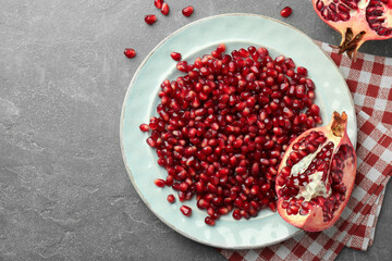 Tasty ripe pomegranate and grains on grey table, flat lay. Space for text