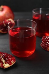 Tasty pomegranate juice in glasses and fresh fruits on black wooden table, closeup