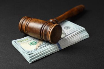 Law gavel with stack of dollars on black table, closeup