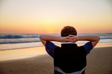 Happy cheerful teenager standing on beach at sunset. happy preteen boy smiling at the camera. Kid...