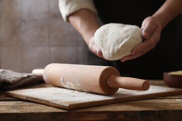 Man making dough at wooden table, closeup