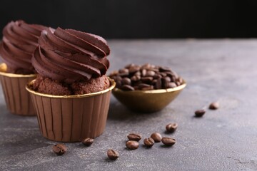 Delicious chocolate cupcakes and coffee beans on grey textured table, closeup. Space for text