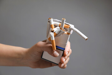 Stop smoking. Woman holding pack with broken cigarettes on grey background, closeup